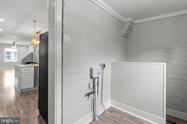 interior space featuring crown molding, ceiling fan, brick wall, and light hardwood / wood-style floors