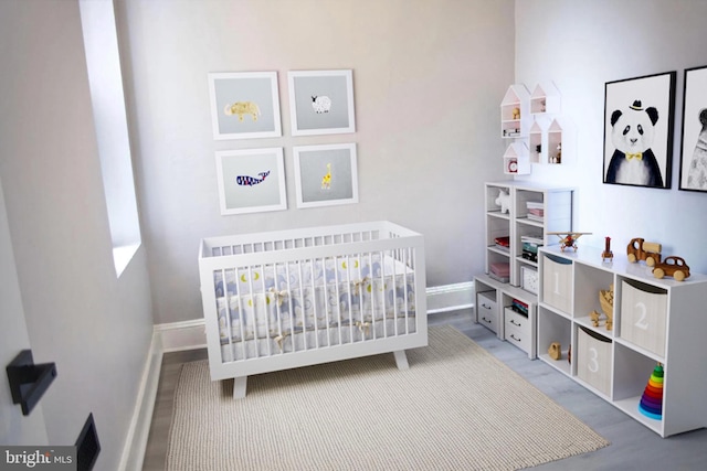 bedroom featuring a nursery area and wood-type flooring