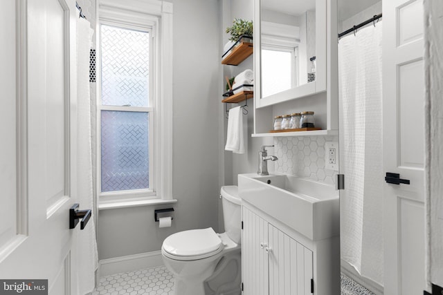 bathroom featuring tile patterned flooring, tasteful backsplash, vanity, and toilet