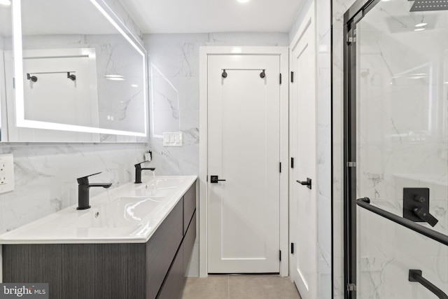 bathroom with vanity, a shower with door, and tile walls