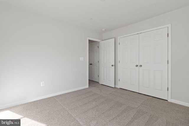 unfurnished bedroom with light carpet and a closet