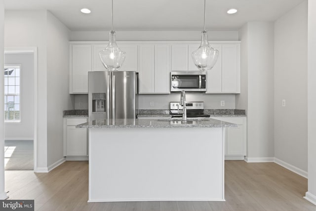 kitchen featuring white cabinetry, appliances with stainless steel finishes, a kitchen island with sink, and light wood-type flooring