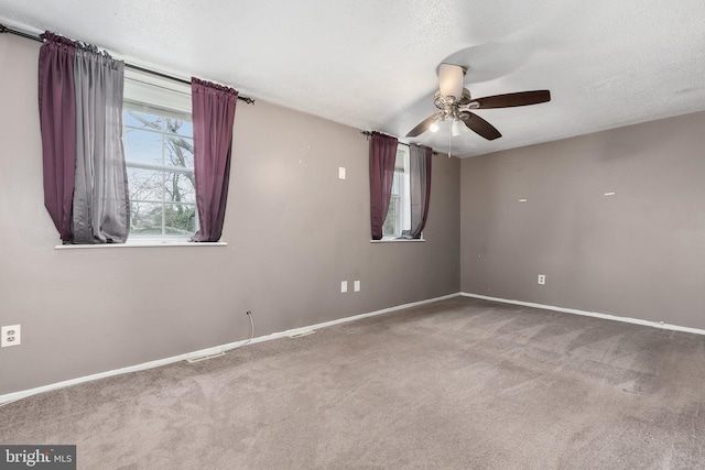 carpeted empty room featuring ceiling fan and a textured ceiling