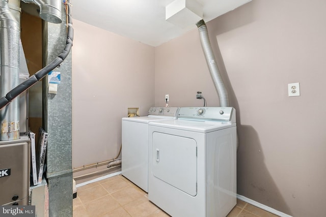 laundry area featuring heating unit, light tile patterned floors, and washing machine and clothes dryer