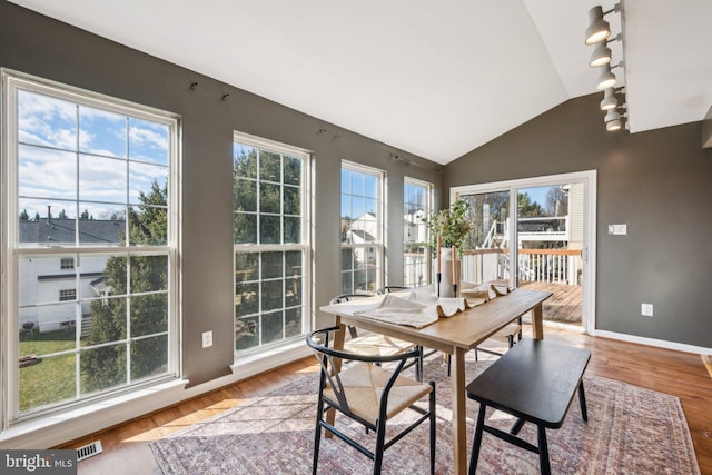 sunroom with lofted ceiling, plenty of natural light, and rail lighting