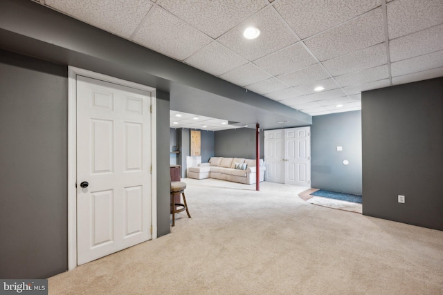 basement featuring a paneled ceiling and light carpet