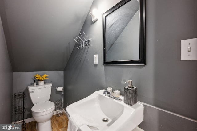 bathroom with lofted ceiling, toilet, sink, and hardwood / wood-style floors