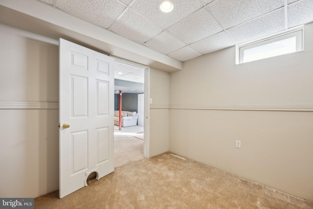 basement with light carpet and a paneled ceiling