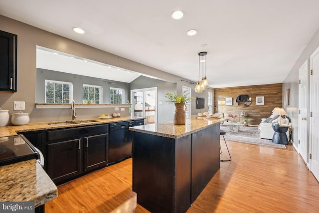 kitchen with pendant lighting, dishwasher, sink, a kitchen breakfast bar, and a center island