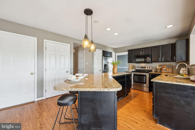 kitchen with sink, hanging light fixtures, stainless steel appliances, light hardwood / wood-style floors, and a kitchen island