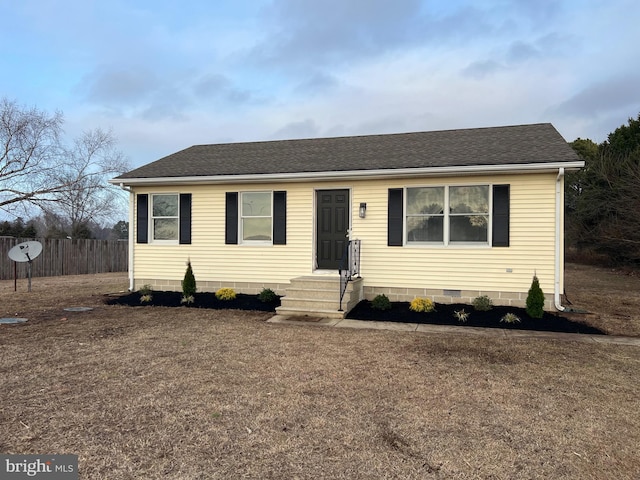 view of front of house with roof with shingles, crawl space, and fence