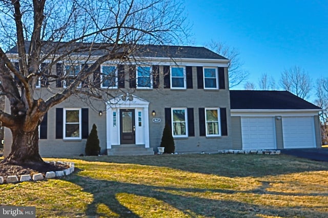 colonial-style house featuring a garage and a front lawn