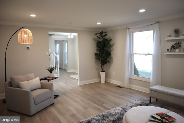 living area featuring ornamental molding and light hardwood / wood-style flooring