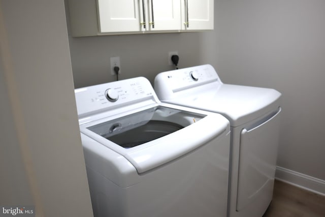 clothes washing area with cabinets, dark hardwood / wood-style floors, and washer and clothes dryer