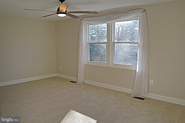 carpeted spare room featuring a wealth of natural light and ceiling fan