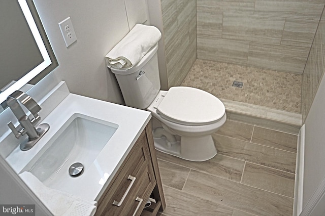 bathroom with vanity, toilet, and a tile shower