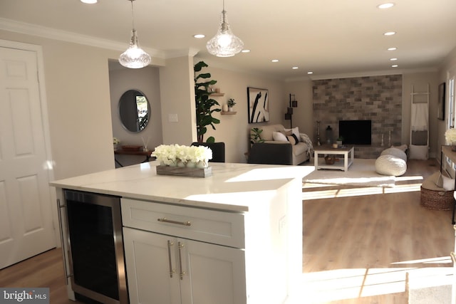 kitchen with white cabinetry, hanging light fixtures, ornamental molding, beverage cooler, and light hardwood / wood-style floors