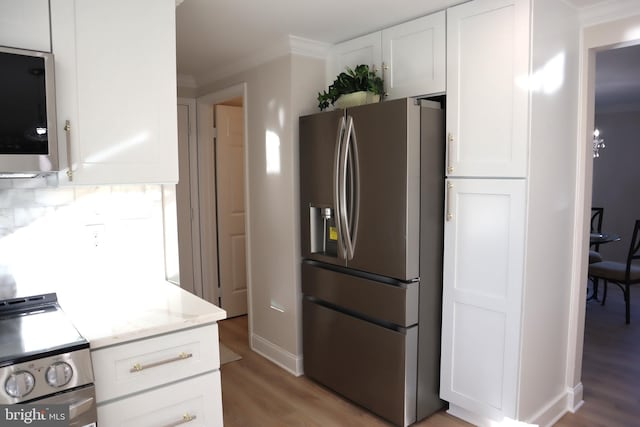 kitchen featuring appliances with stainless steel finishes, white cabinets, decorative backsplash, light stone countertops, and light wood-type flooring