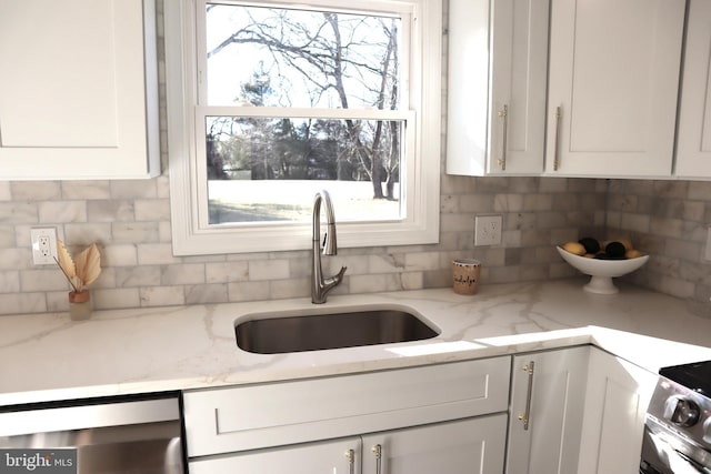 kitchen with tasteful backsplash, sink, light stone countertops, and white cabinets