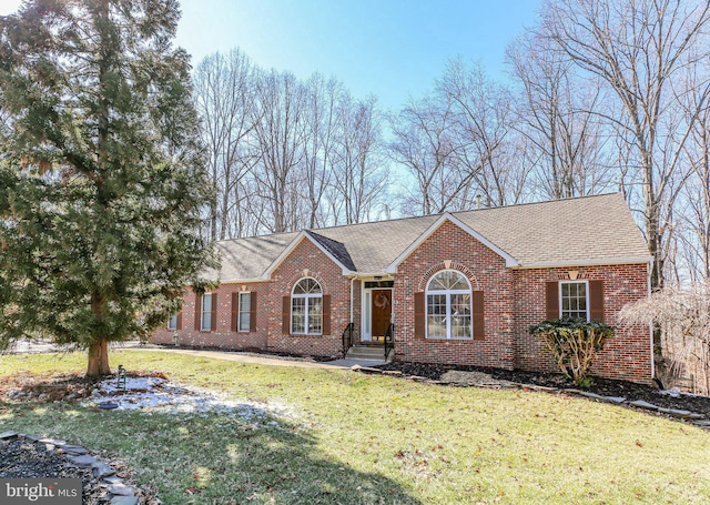 ranch-style home with a front lawn, roof with shingles, and brick siding