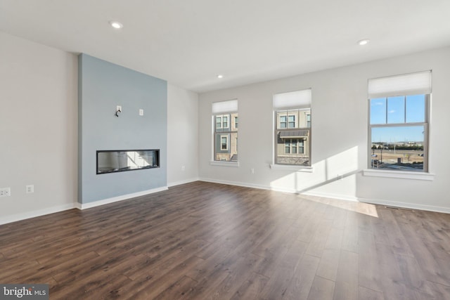 unfurnished living room with dark hardwood / wood-style flooring and a healthy amount of sunlight