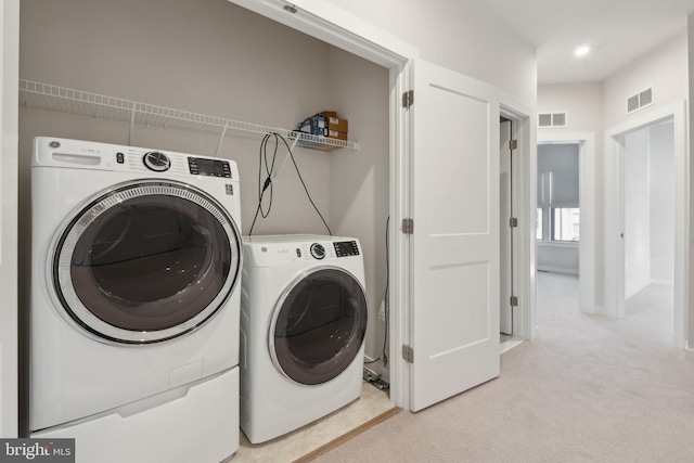 laundry area featuring light carpet and washing machine and dryer