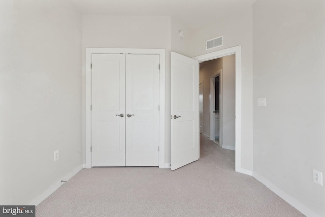 unfurnished bedroom featuring light colored carpet and a closet