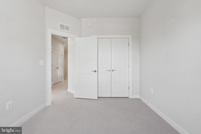 unfurnished bedroom with light carpet and a closet