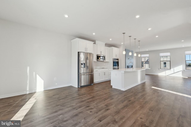 kitchen featuring white cabinetry, stainless steel appliances, dark hardwood / wood-style floors, a center island with sink, and decorative light fixtures