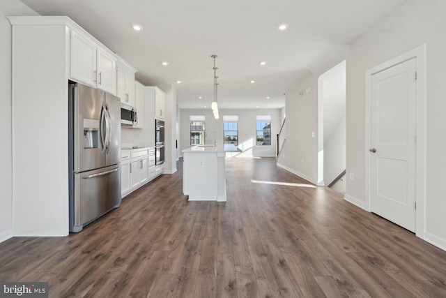 kitchen with appliances with stainless steel finishes, an island with sink, hanging light fixtures, and white cabinets