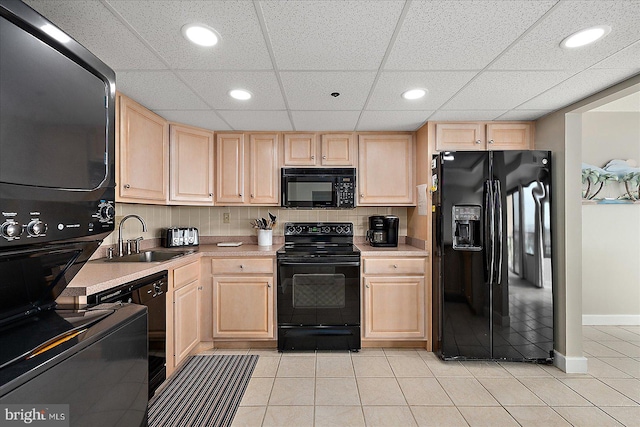 kitchen featuring stacked washing maching and dryer, sink, light brown cabinets, and black appliances