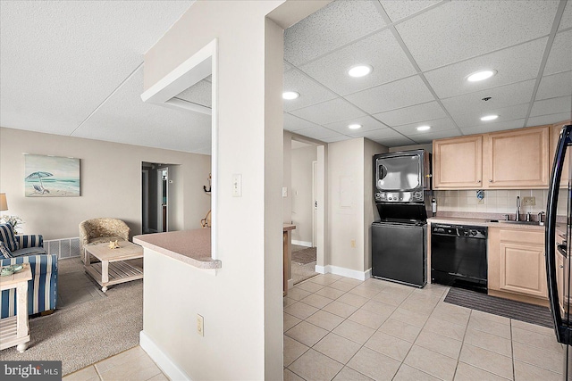 kitchen featuring sink, light tile patterned floors, light brown cabinets, dishwasher, and stacked washing maching and dryer