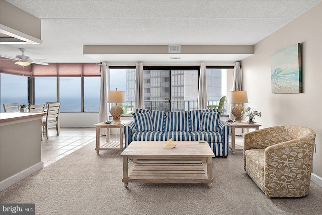 living room featuring ceiling fan, carpet floors, a textured ceiling, and a water view