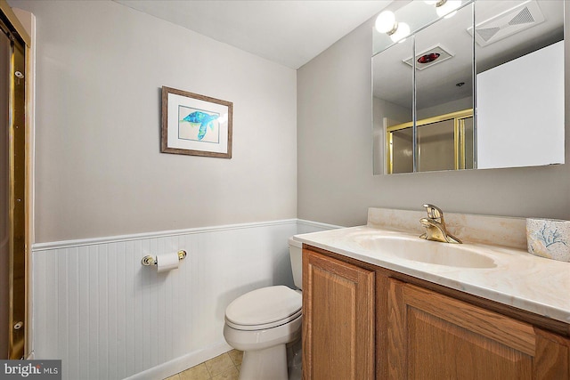 bathroom featuring vanity, a shower with shower door, tile patterned floors, and toilet