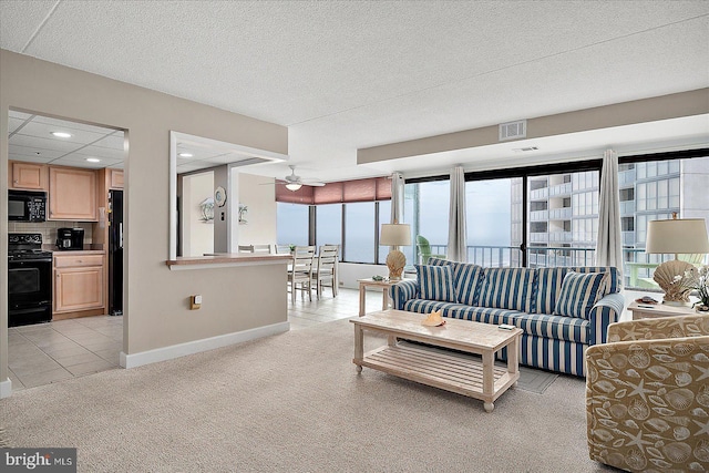 living room with ceiling fan, light carpet, and a textured ceiling