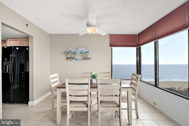 sunroom / solarium with a water view, ceiling fan, and a view of the beach