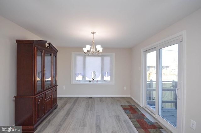 unfurnished dining area with a chandelier, light wood finished floors, and baseboards