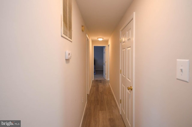 corridor with wood finished floors, visible vents, and baseboards