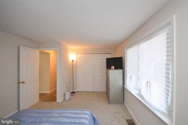 bedroom featuring light carpet, a closet, visible vents, and baseboards