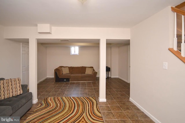 basement featuring dark tile patterned floors, visible vents, and baseboards