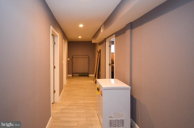 corridor featuring baseboards, light wood-type flooring, and recessed lighting