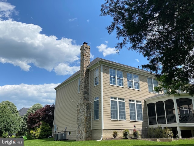 rear view of property with a lawn and a sunroom