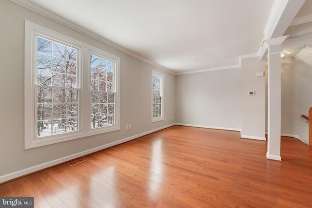 unfurnished living room featuring ornamental molding, light wood-type flooring, and ornate columns