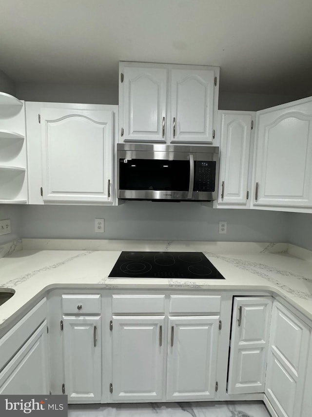 kitchen featuring white cabinetry, light stone countertops, and black electric stovetop