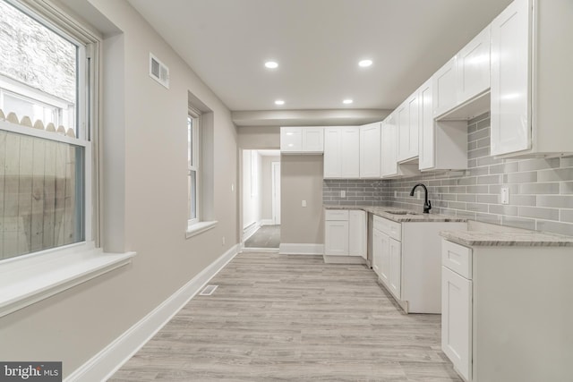 kitchen with light stone counters, backsplash, visible vents, and white cabinets