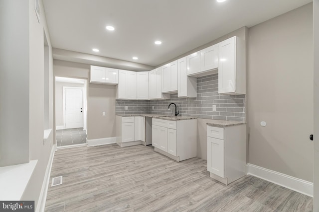 kitchen featuring visible vents, white cabinetry, and a sink