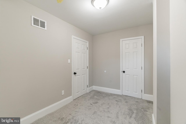 unfurnished room with visible vents, light carpet, and baseboards