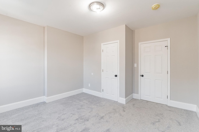 unfurnished bedroom featuring light carpet and baseboards