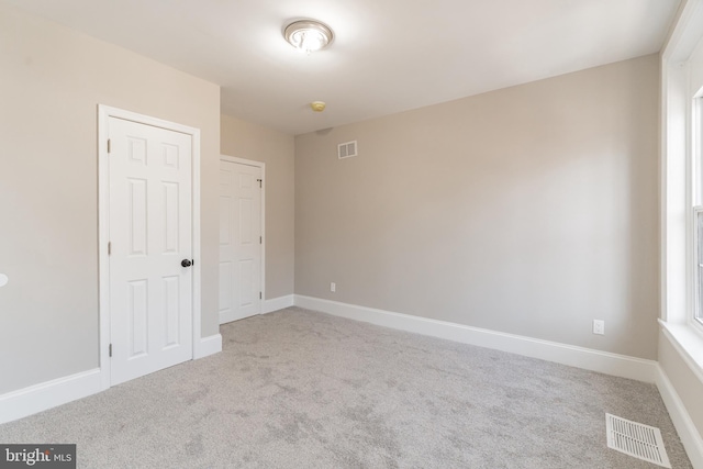 unfurnished room with light carpet, visible vents, and baseboards