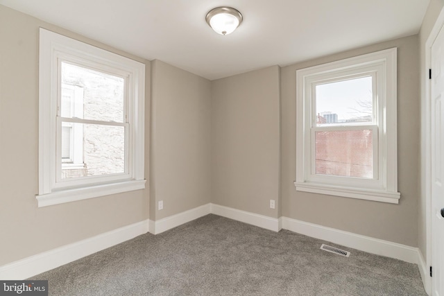 carpeted spare room with visible vents and baseboards